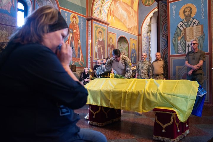 A woman cries near a coffin and Ukrainian military members pay their respects during the farewell ceremony for serviceman Serhii Radiuk on Sept. 25 in Kyiv, Ukraine.